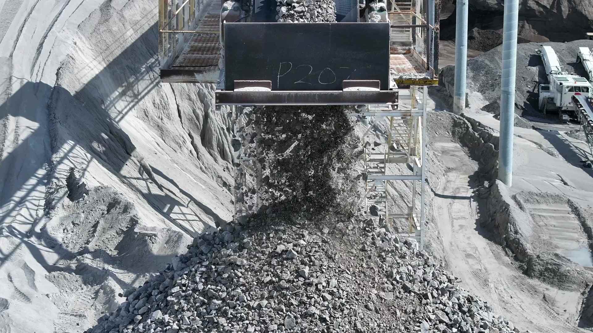 A loader tipping rock into a crusher at a processing plant